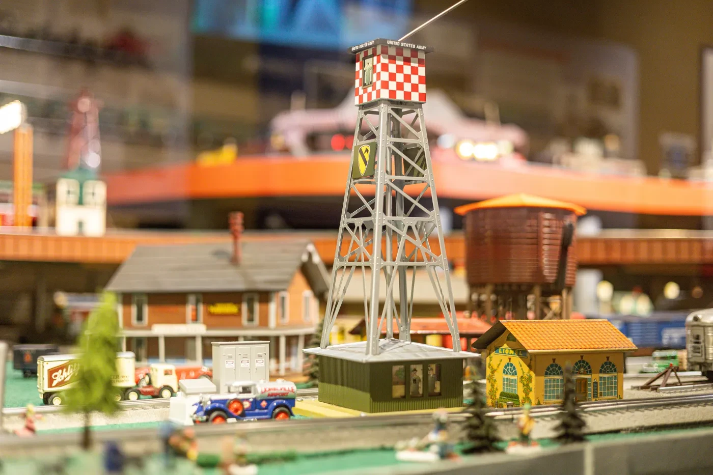 Model train set with buildings and a tall metal tower.